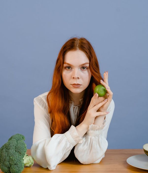 Woman holding a serene yoga pose in a dark studio with lime green light.